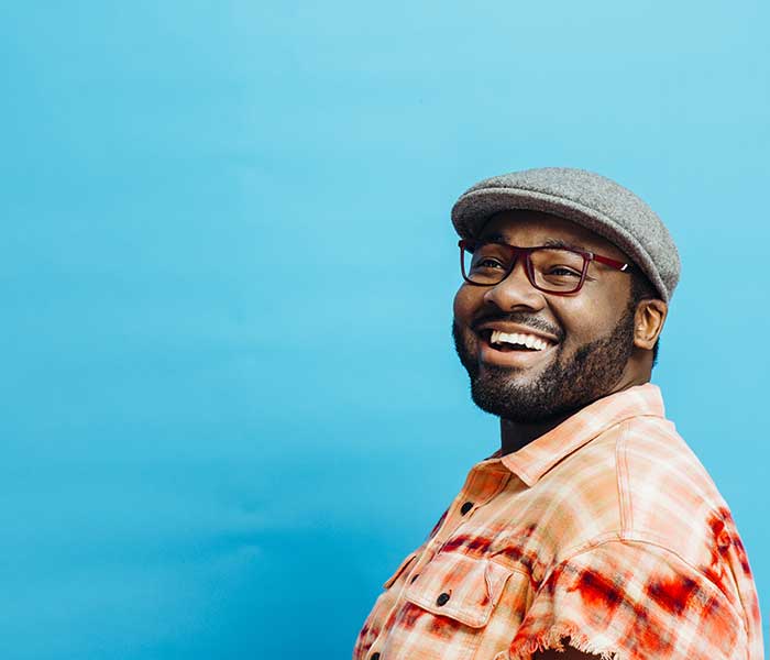 Happy man in orange shirt looking up, with blue copy space around him