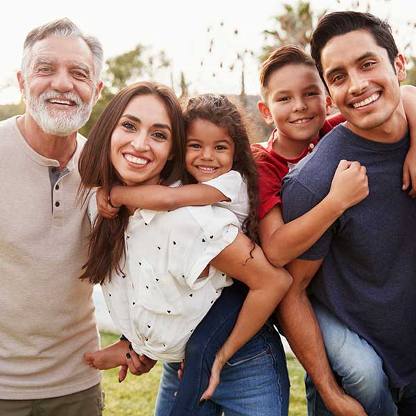 Three generation Hispanic family standing in the park, smiling to camera