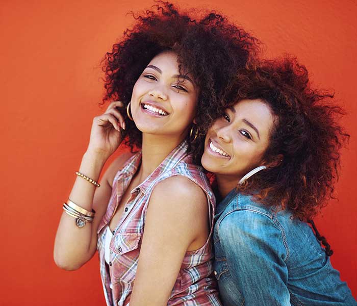 Shot of two young friends posing against a red background