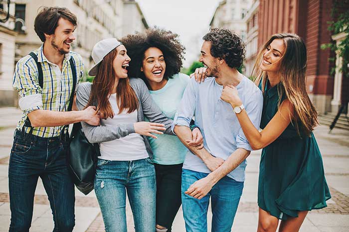 Group of mixed race people laughing and walking outdoors in the city